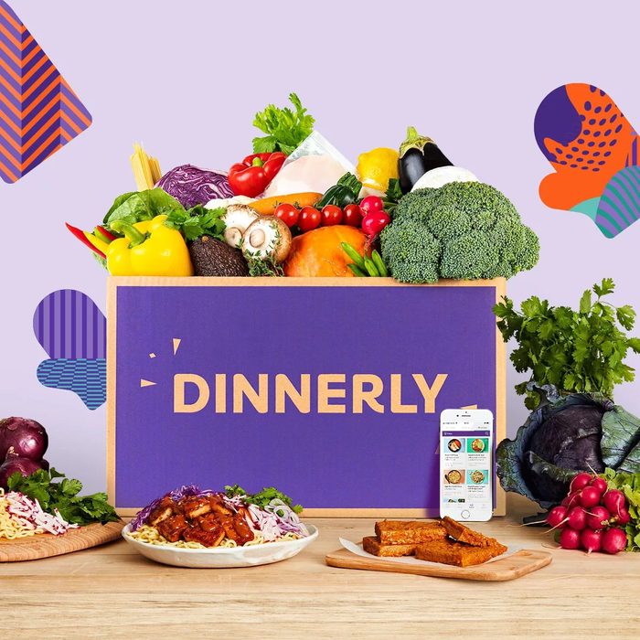 Box filled with colorful vegetables sits on a table, accompanied by prepared meals. Text reads 