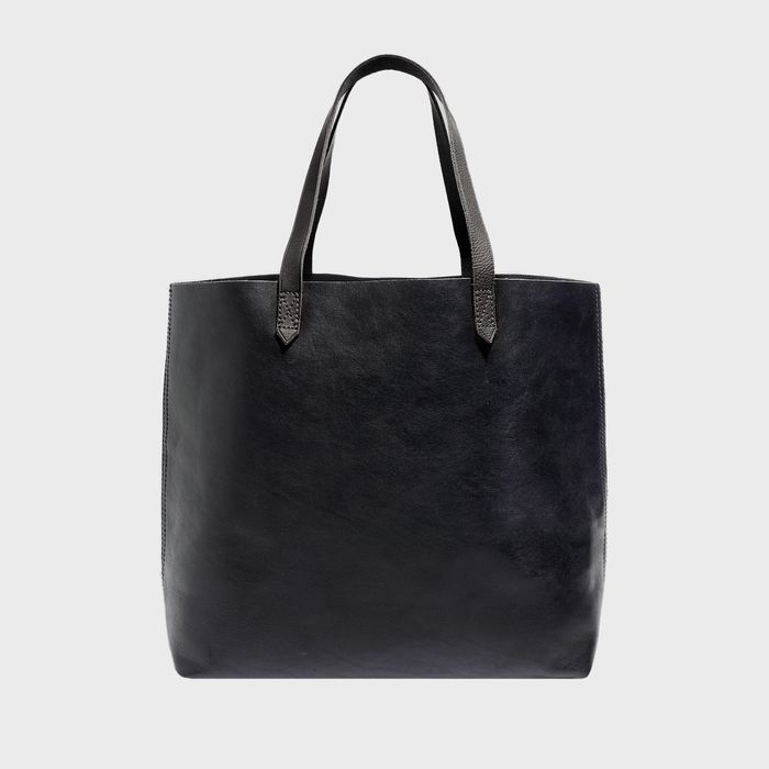 A black leather tote bag sits upright with handles extended, against a plain light gray background.