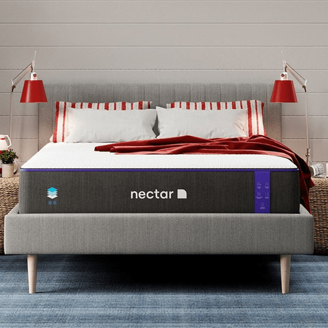 A bed displays red-striped pillows and a red blanket, situated in a modern bedroom with two red lamps. The mattress is labeled 