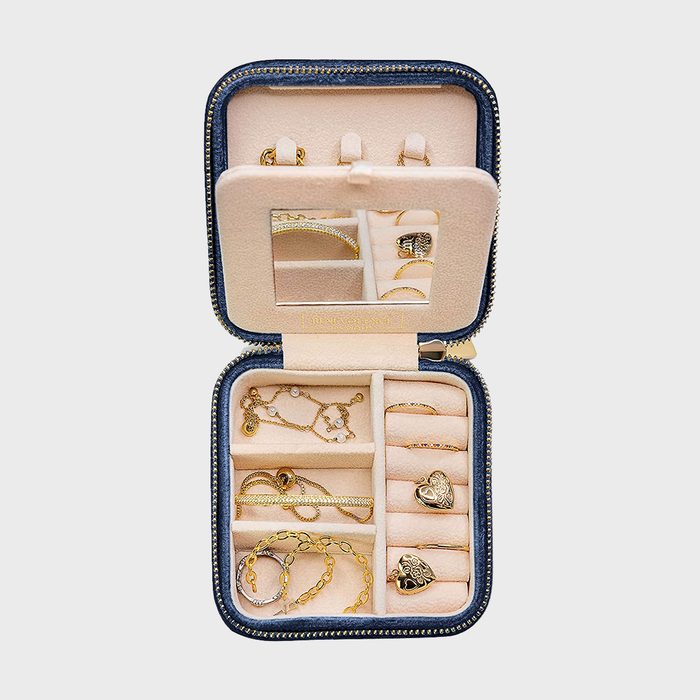 Jewelry box holding assorted gold pieces, arranged neatly inside small compartments, with a mirror in the lid, surrounded by a soft interior and case.