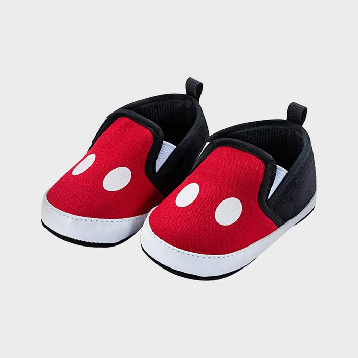 Red and black baby shoes with white polka dots rest on a white surface, featuring tabs on the back for easy grip.