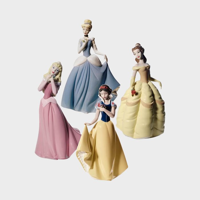Four ceramic princess figurines, each posing elegantly, stand together wearing different colored gowns on a plain white background.