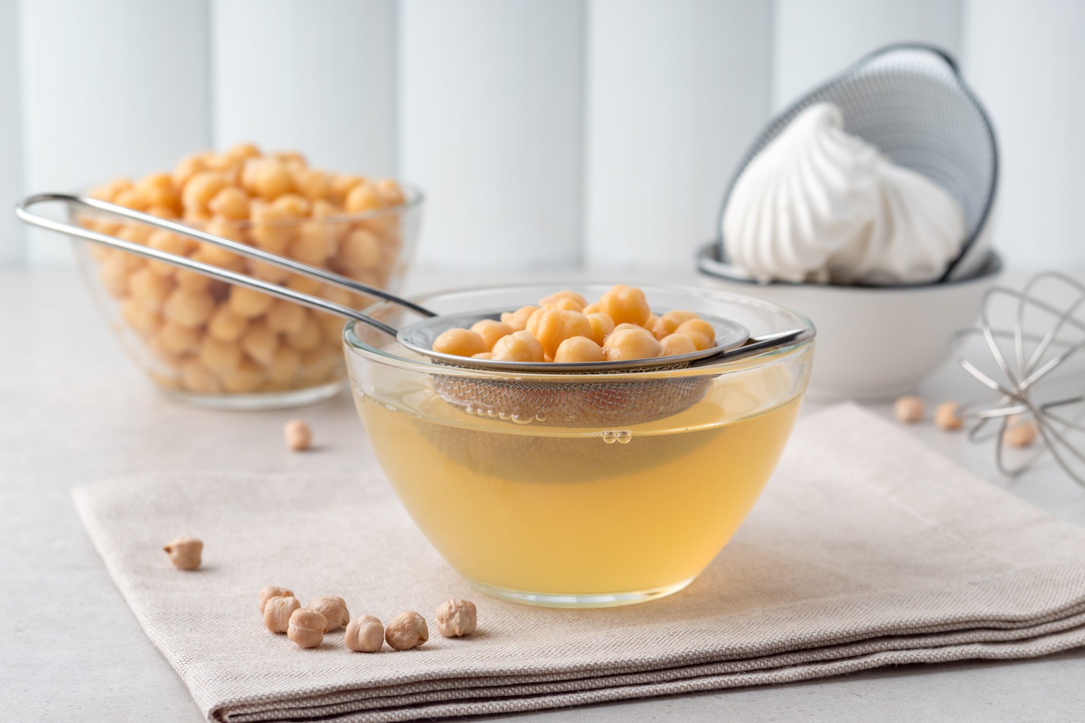 Composition with aquafaba, boiled chickpeas and meringues on grey table. Egg replacement for vegan cooking