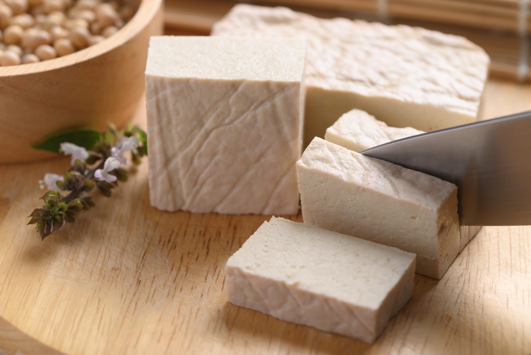 Fresh Tofu cutting by kitchen knife on wooden board