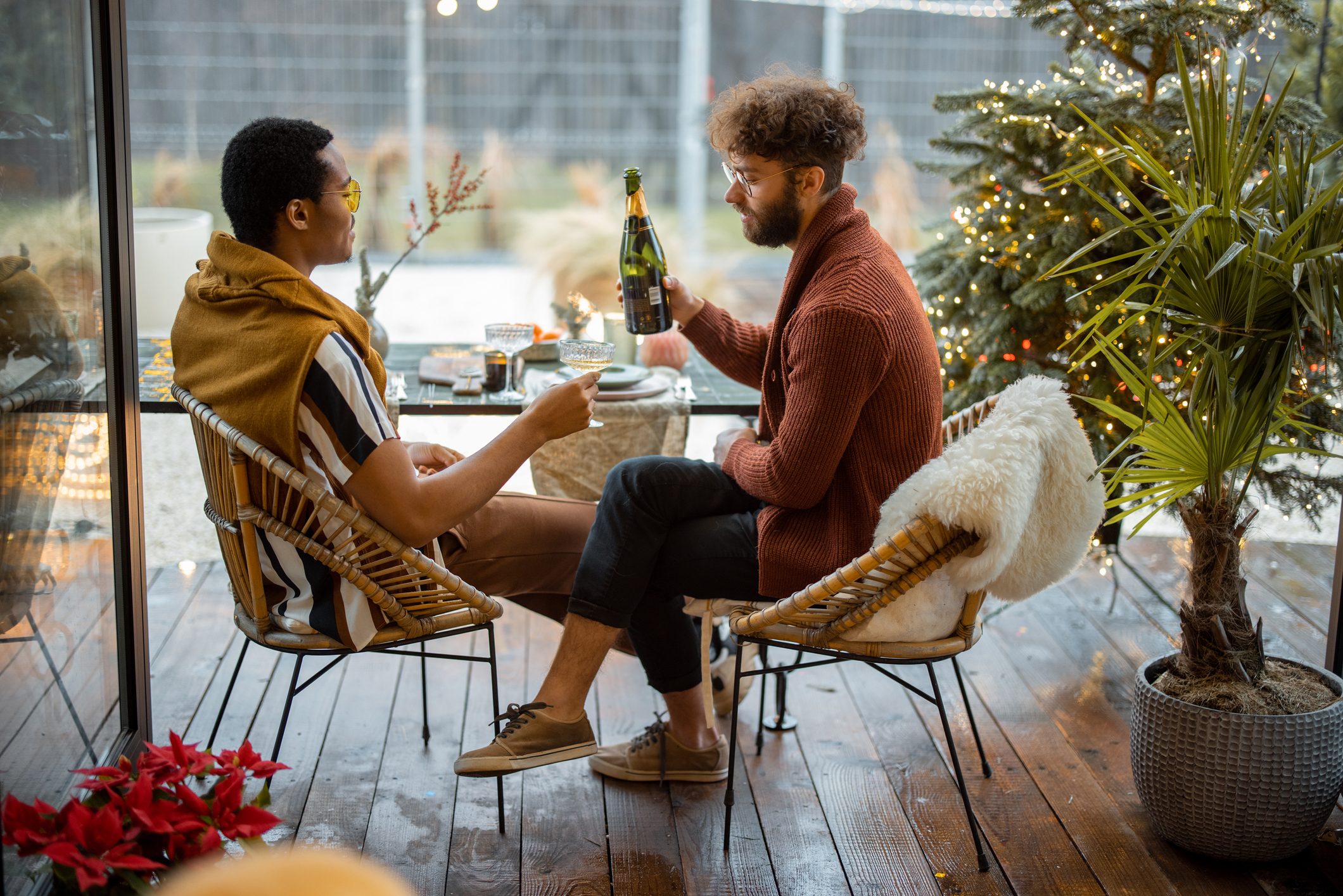 Two male friends celebrating winter holidays at backyard