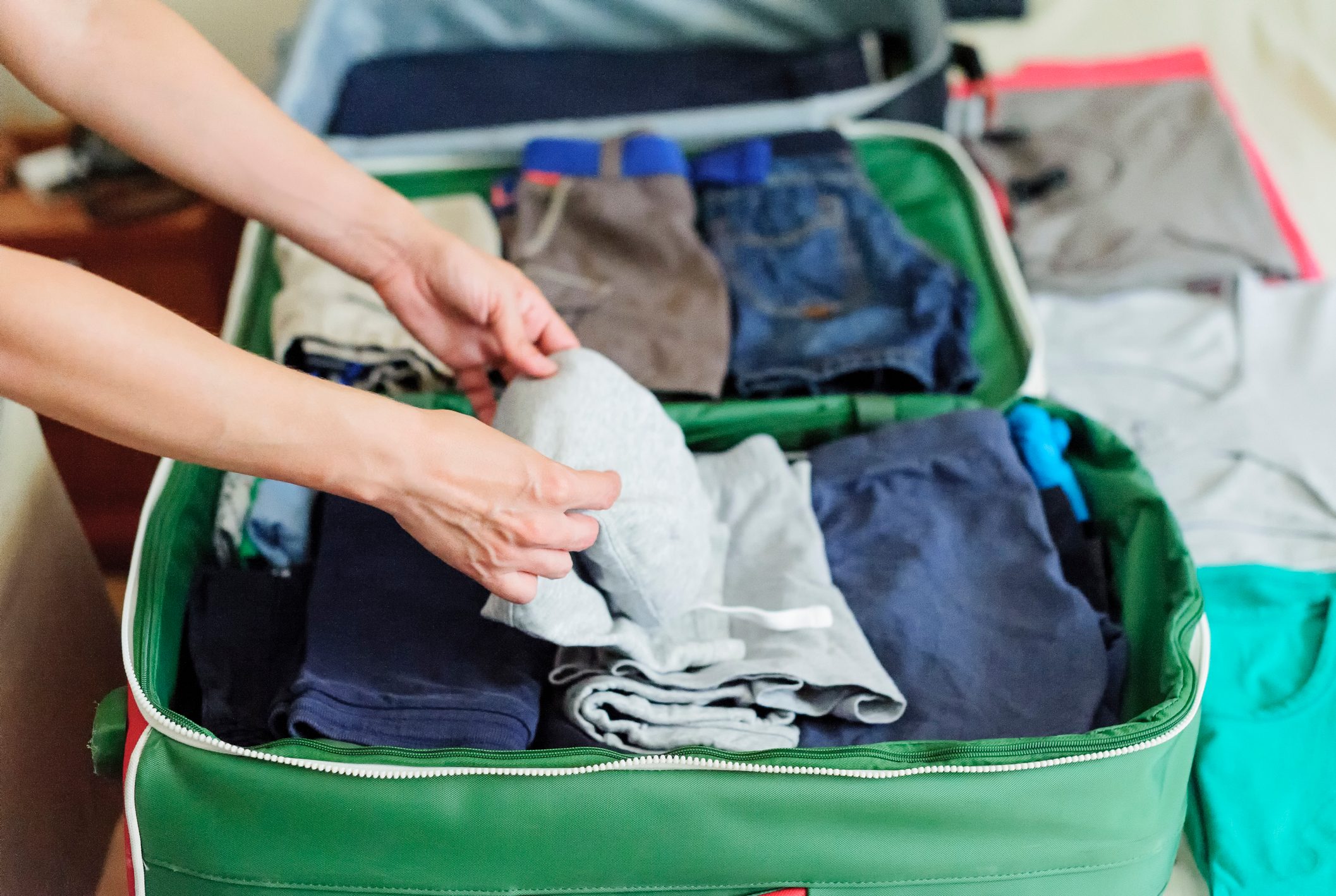 Close up of Woman hands packing suitcase on the bed