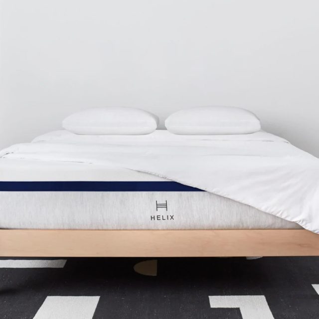 Bed with white sheets and pillows; mattress is labeled 