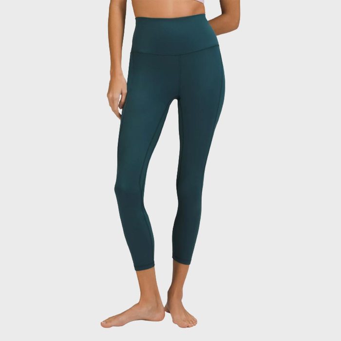 Person wearing dark teal leggings stands barefoot against a plain background, showcasing the high-waisted athletic wear.