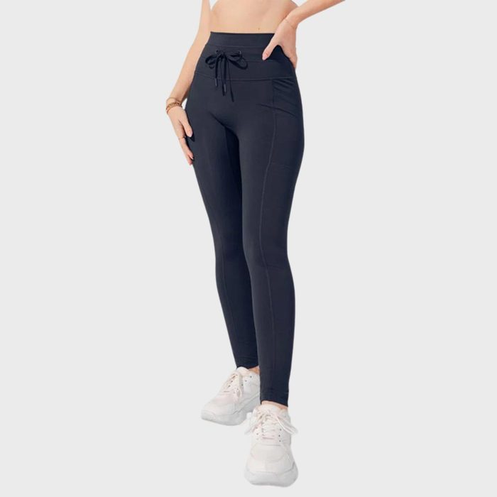 Black leggings worn by a person, standing with hands on hips, against a plain light background.