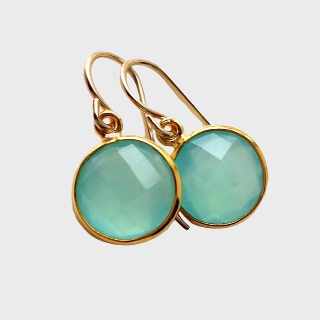 Two circular aqua gemstones set in gold earrings dangle against a plain white background.