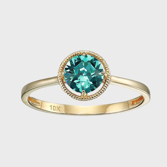 Gold ring showcases blue gemstone, surrounded by rope design, with 