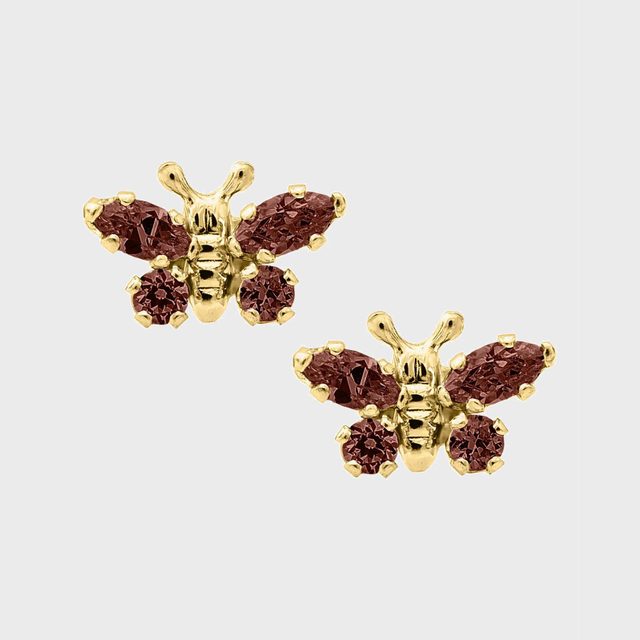 Gold butterfly earrings feature maroon gemstones as wings, set against a plain, light gray background.