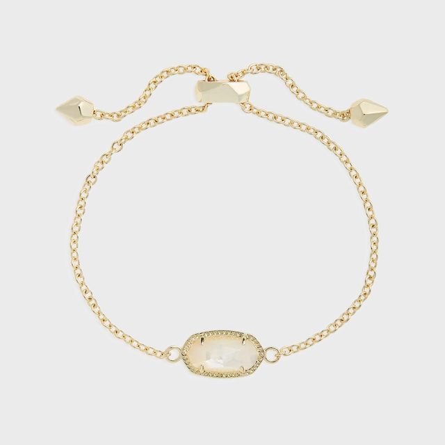 Gold bracelet features an oval gemstone centerpiece, adjustable chain with cone-shaped ends, on a white background.