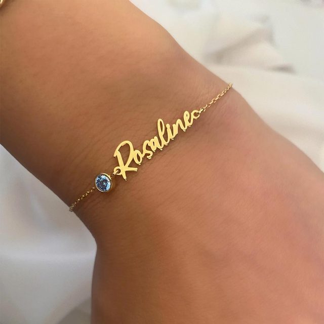 Gold bracelet rests on a wrist, displaying the name 