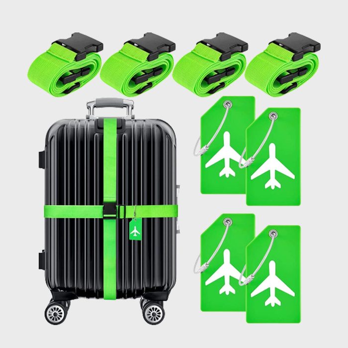 A black suitcase with green straps and tags, displaying an airplane icon, is surrounded by four rolled-up straps and four tags.