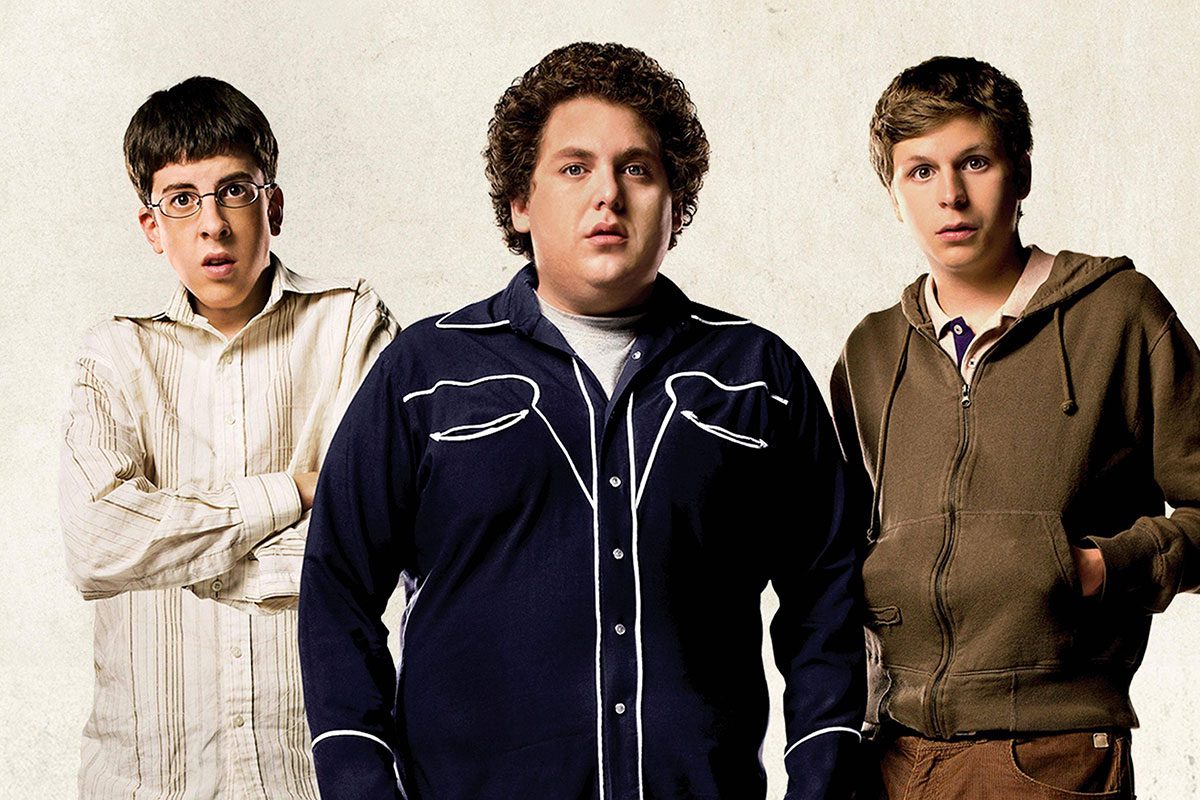 Three young men stand facing forward, displaying varied expressions against a plain light background.
