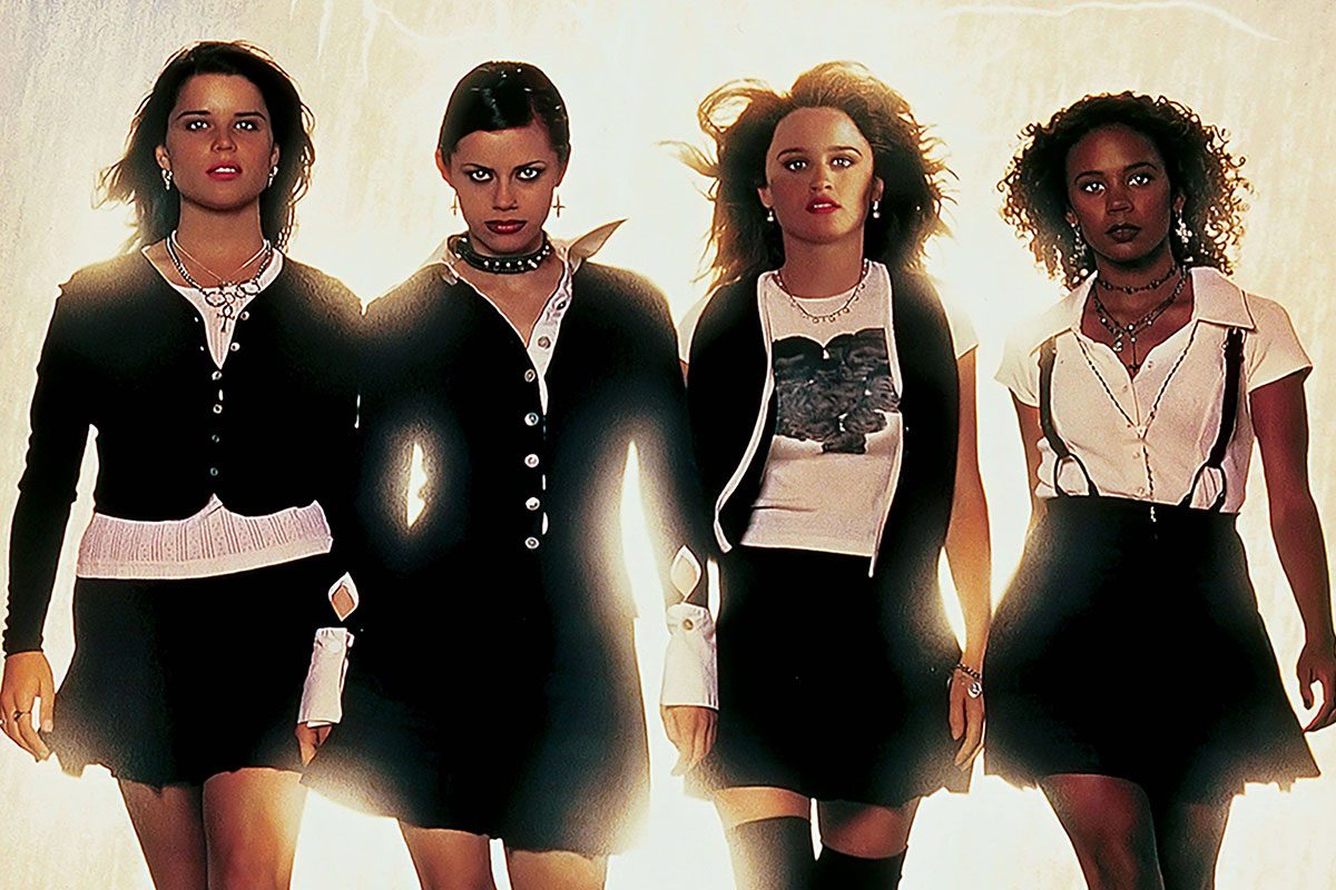 Four women walk confidently, dressed in coordinated dark clothing, against a bright, backlit background.
