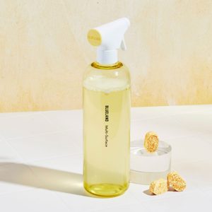 Spray bottle sits on a tiled surface beside three tablets. Text: 
