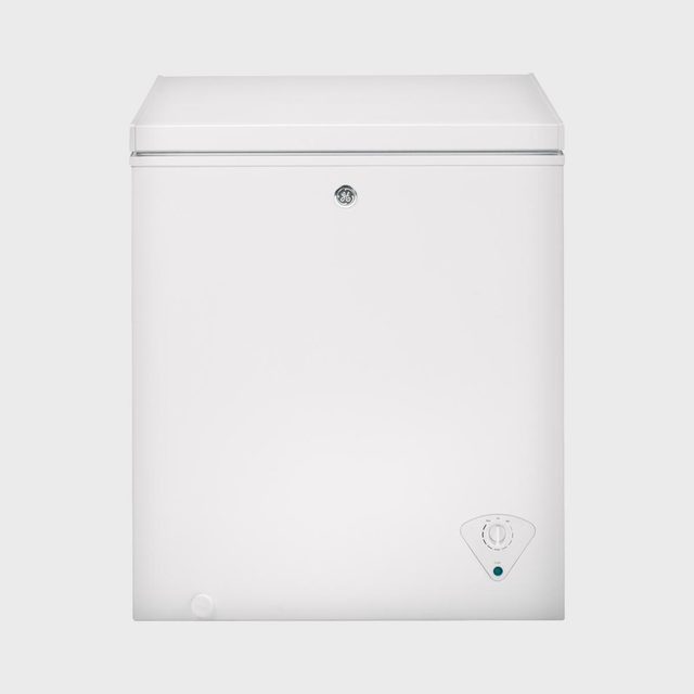 White chest freezer appears closed, displaying a temperature control dial at the bottom corner, against a plain background.
