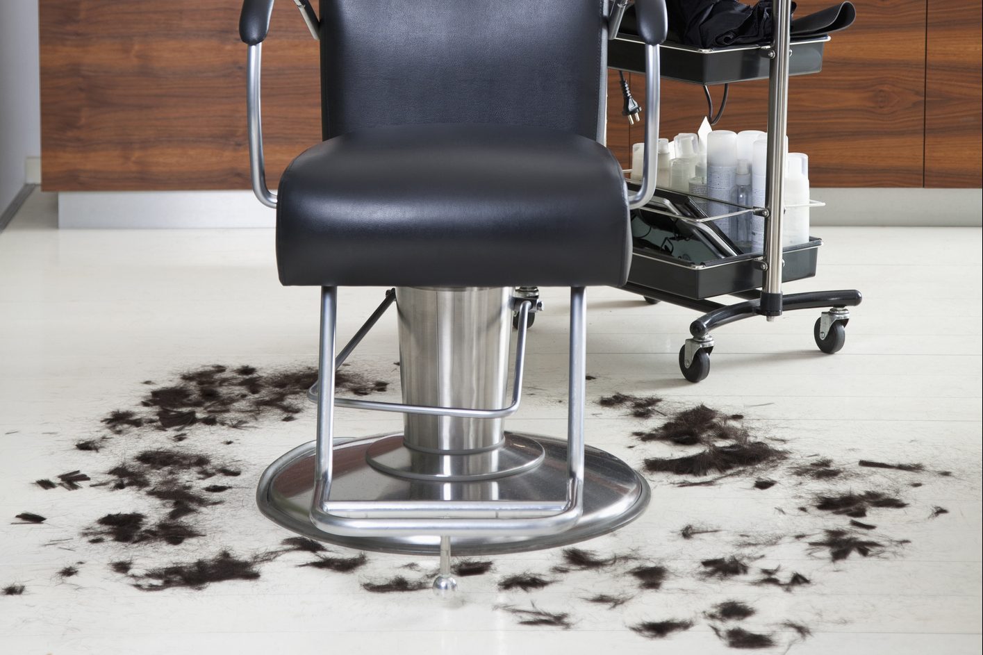 An empty barber chair with cut hair around it