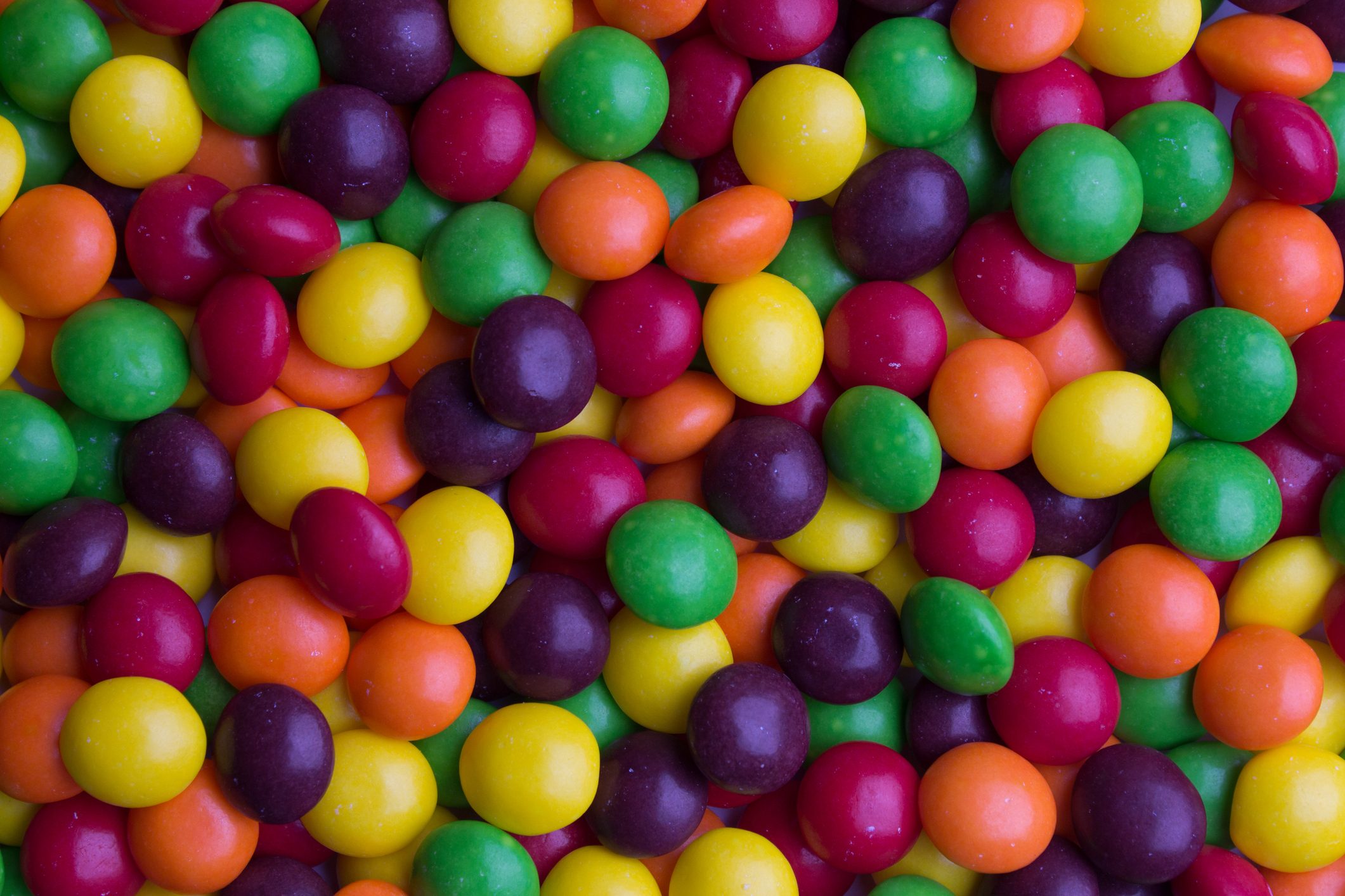 Colorful candies lie scattered, creating a vibrant, dense pattern.
