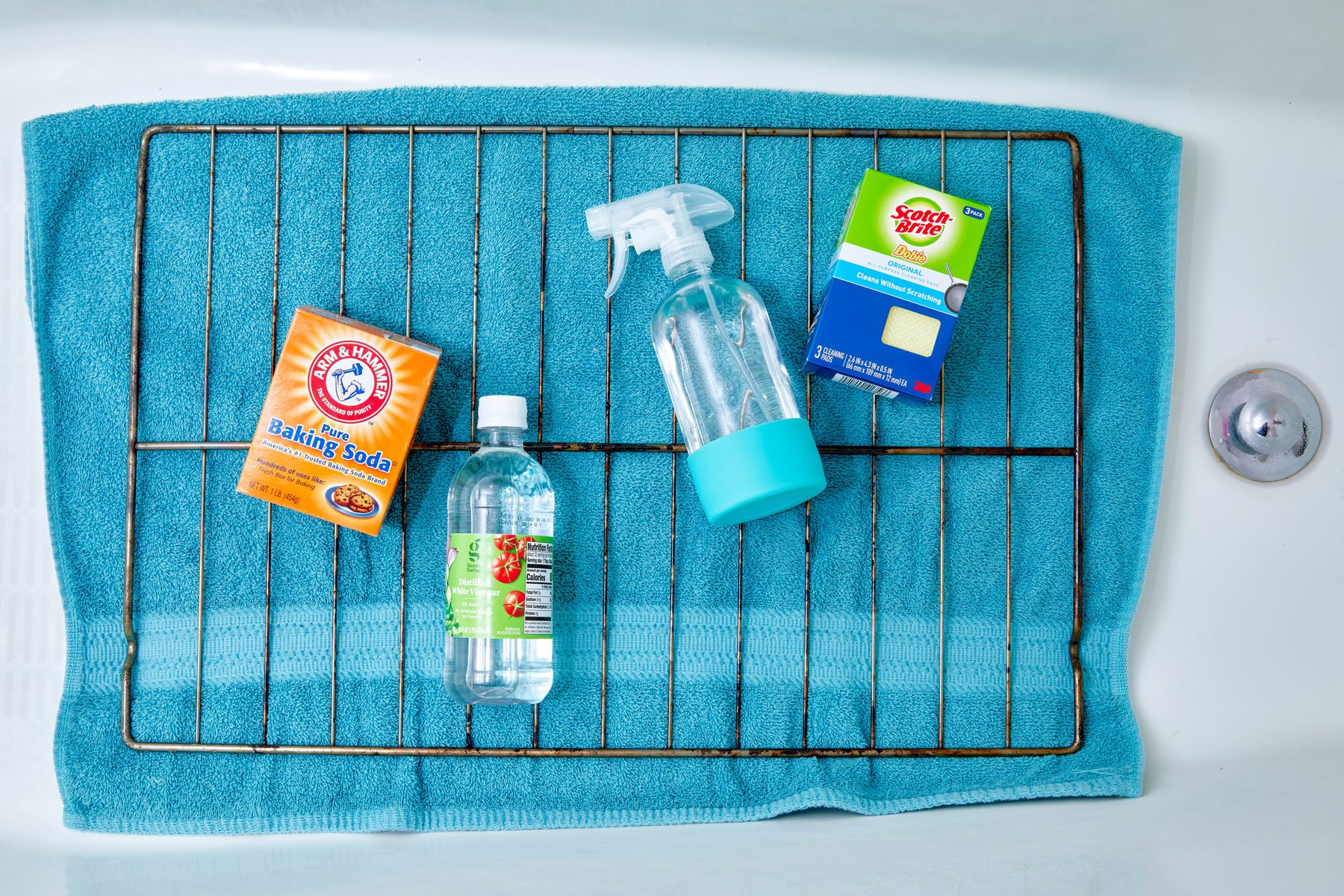 oven rack and cleaning supplies laid out in a bathtub