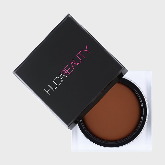 Cosmetic container displays brown product with a partially open black lid. 