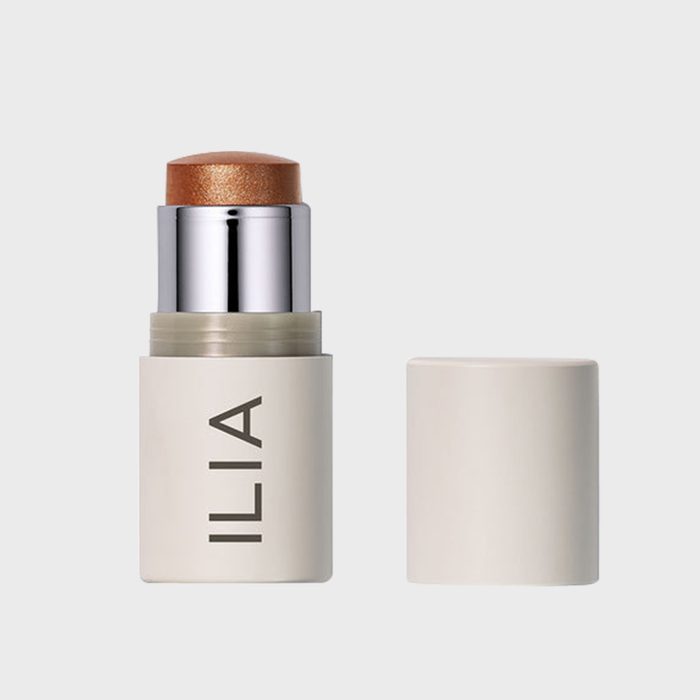 A makeup stick with visible bronze color extends from a cream container labeled 