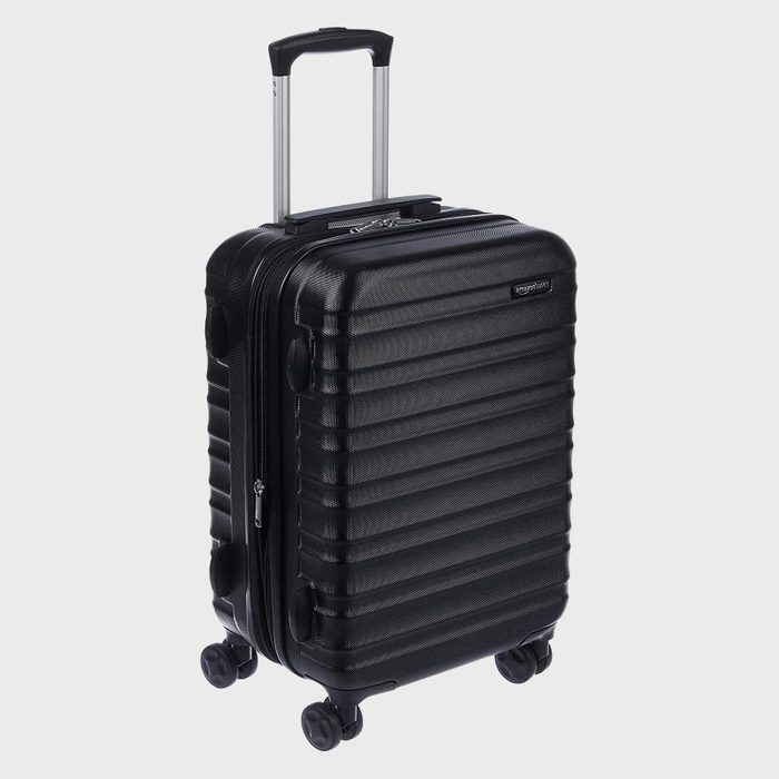 A black, hard-shell suitcase stands upright; it has four wheels and a telescopic handle, set against a plain white background.