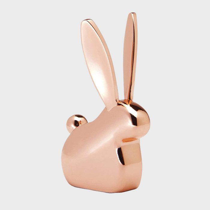 Copper-colored rabbit sculpture standing upright on a light gray background, displaying elongated ears and a rounded body.