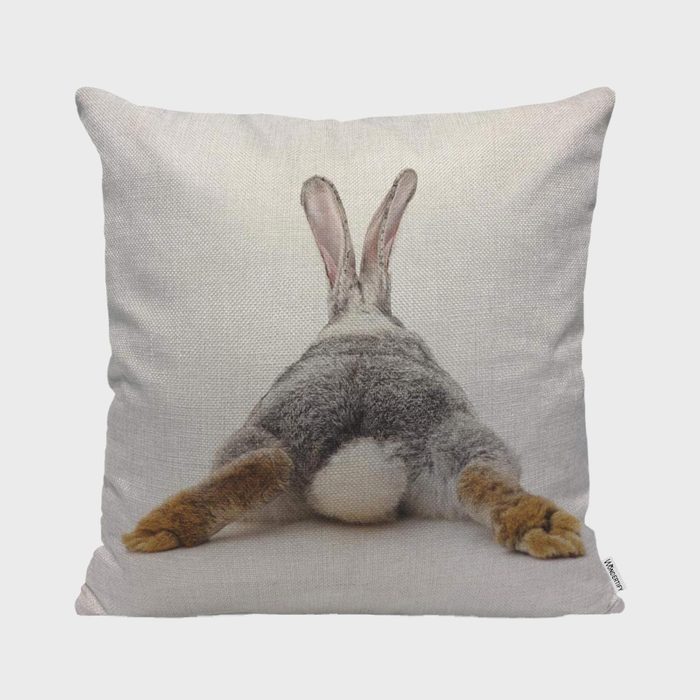A cushion displays a rabbit lying on its stomach with ears upright, set against a plain background.