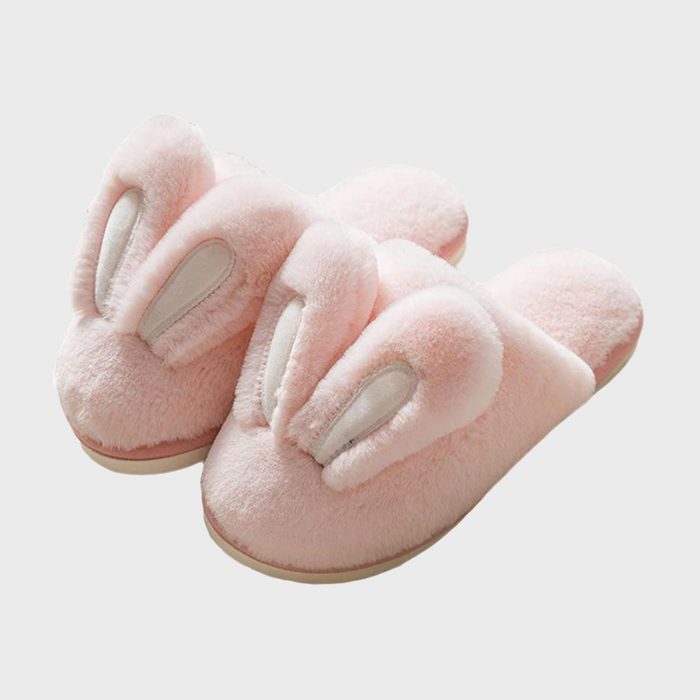 Pink fluffy slippers featuring bunny ears, resting against a plain white background.