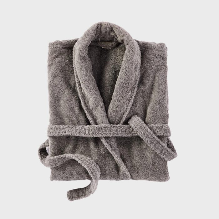 Gray bathrobe lies folded with its belt wrapped, against a plain white background.