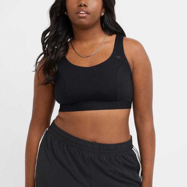 Person wearing a black sports bra and pants stands against a plain background.