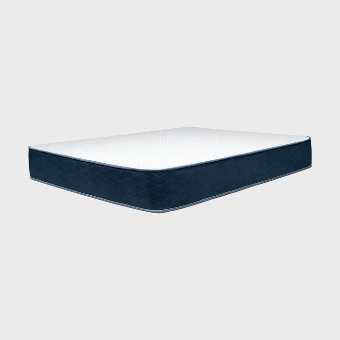 A rectangular mattress sits in a plain, neutral space, featuring a white top and blue quilted sides.