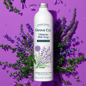 Bottle stands upright, displaying dish soap label, surrounded by fresh lavender and thyme on a purple background.