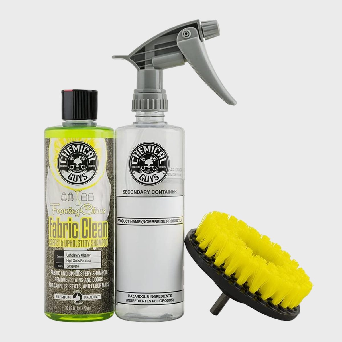 Bottle stands upright, labeled "Chemical Guys Fabric Clean." Sprayer and brush rest beside, all against a plain white background.