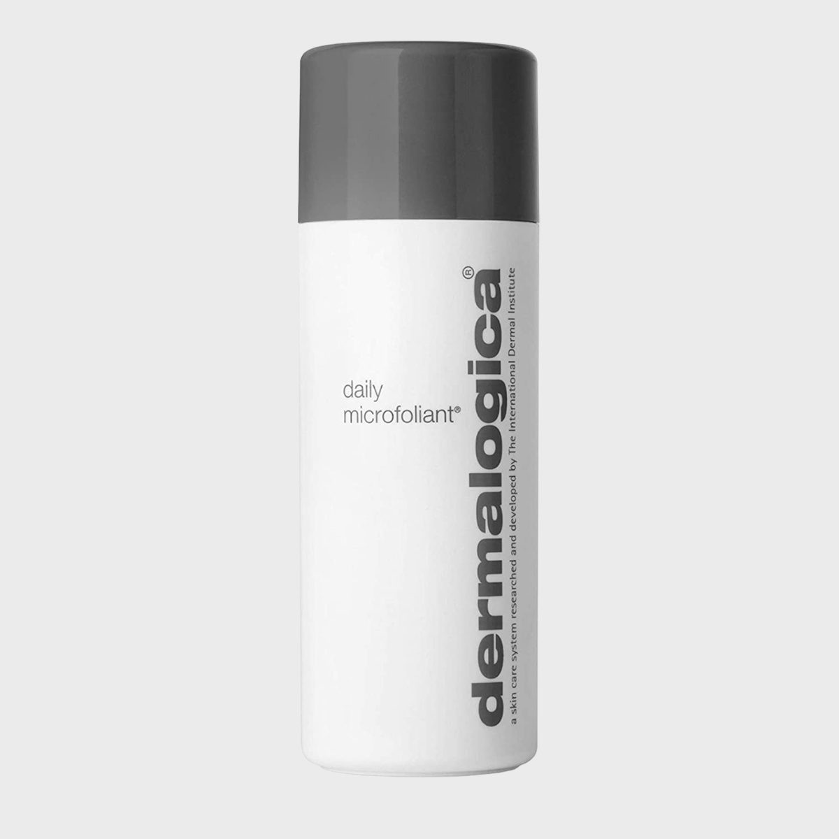 A white cylindrical bottle displays "dermalogica" vertically, labeled "daily microfoliant," with a dark gray cap, in a plain studio setting.
