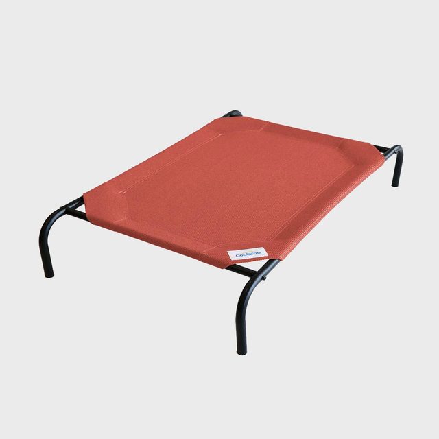 Red pet bed rests on black metal legs, set against a plain white background. Small tag reads 