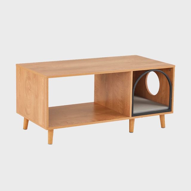 Wooden coffee table features two open compartments; one includes an arched metal frame with a circular opening, placed in a minimalist setting.