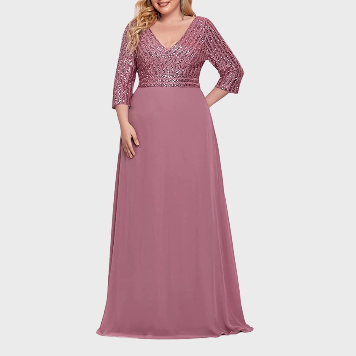 A woman wears an elegant, long pink gown with sequin embellishments, standing against a plain white background.