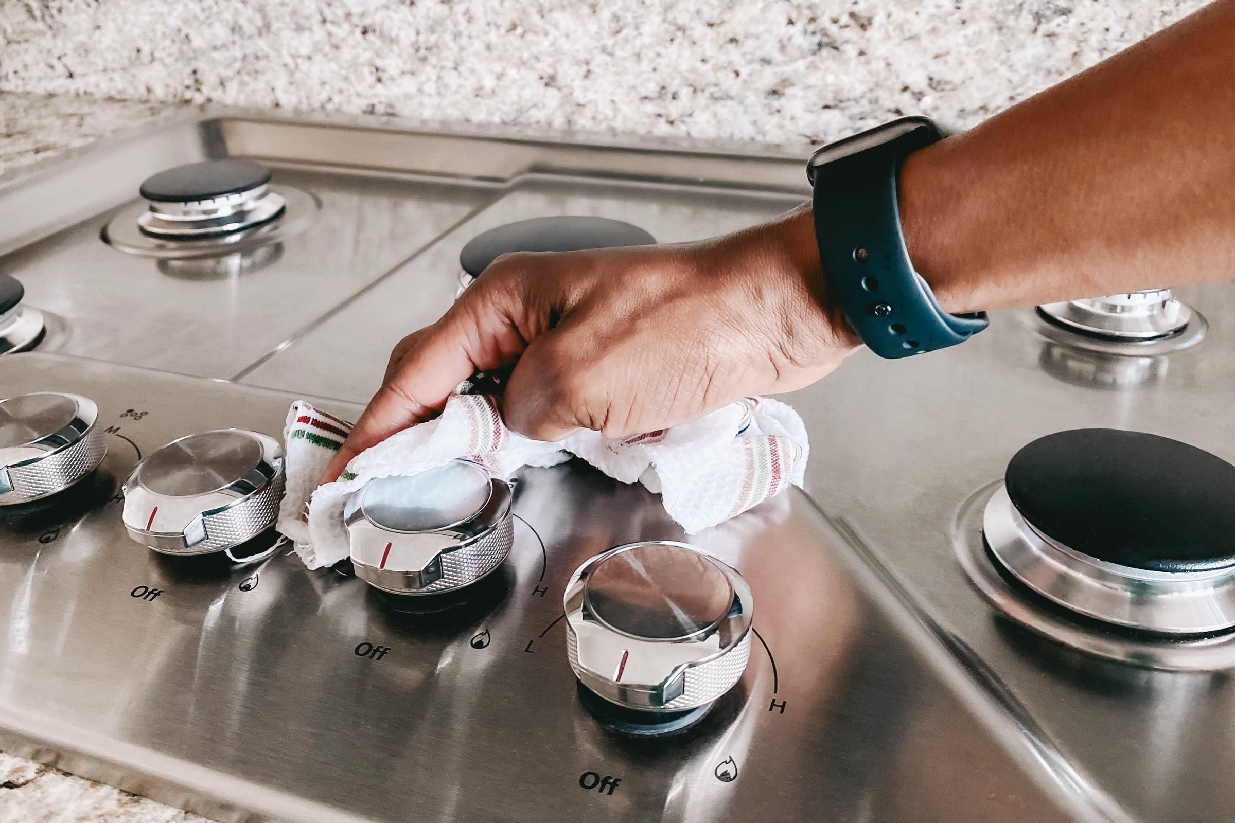 hand cleaning a stove top with a rag