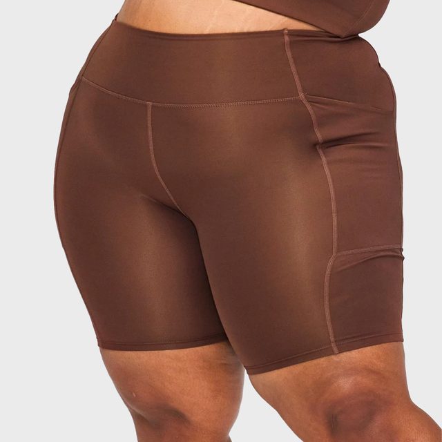 Brown biker shorts rest on a person's thighs against a plain background.