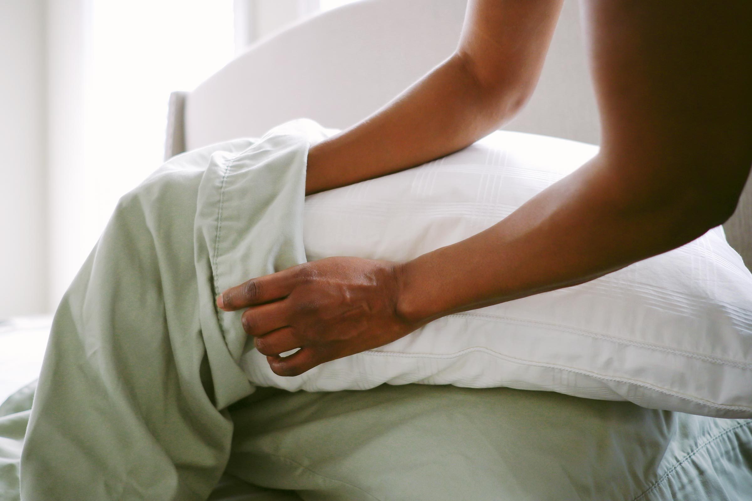 woman's hands putting a pillowcase onto a pillow