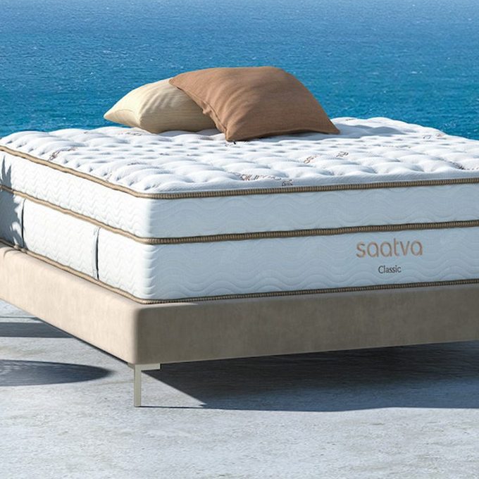 Mattress sits on platform bed; ocean background. Two pillows rest on top. Text reads 