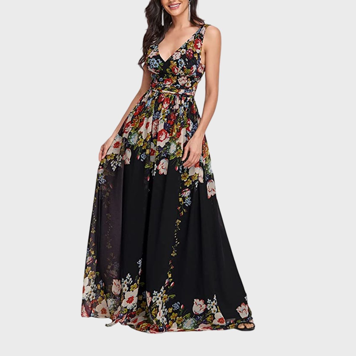 A woman wears a flowing black floral-patterned dress with a fitted top and flared skirt, set against a plain white background.