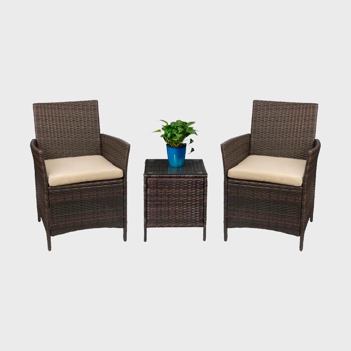 Two wicker chairs with cushions flank a matching table, supporting a blue pot with a green plant, against a plain background.