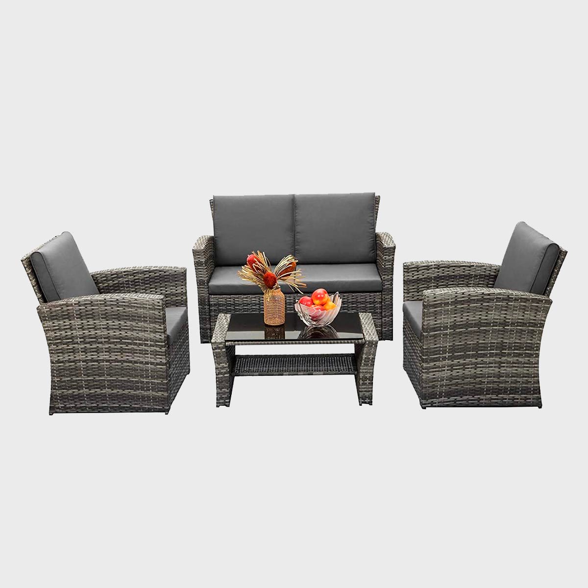 Wicker patio set with two chairs and a loveseat surrounds a glass table adorned with a vase of flowers and a fruit bowl.