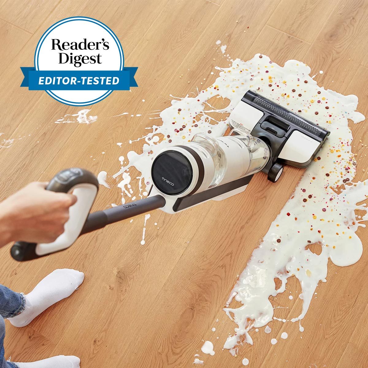 Vacuum cleaner cleans spilled milk and cereal on a wooden floor. A "Reader's Digest Editor-Tested" seal is visible in the top left.