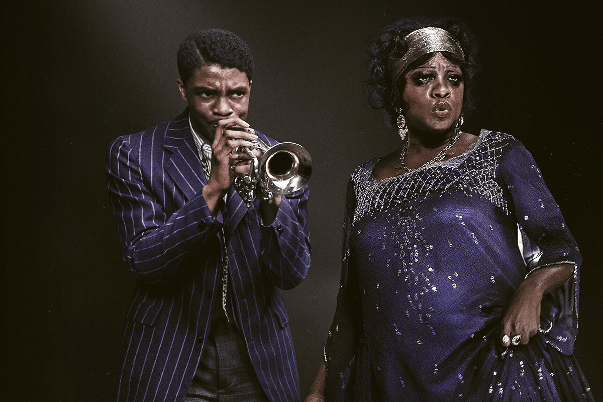 A man plays a trumpet while a woman in a sequined gown sings, both against a dark backdrop.